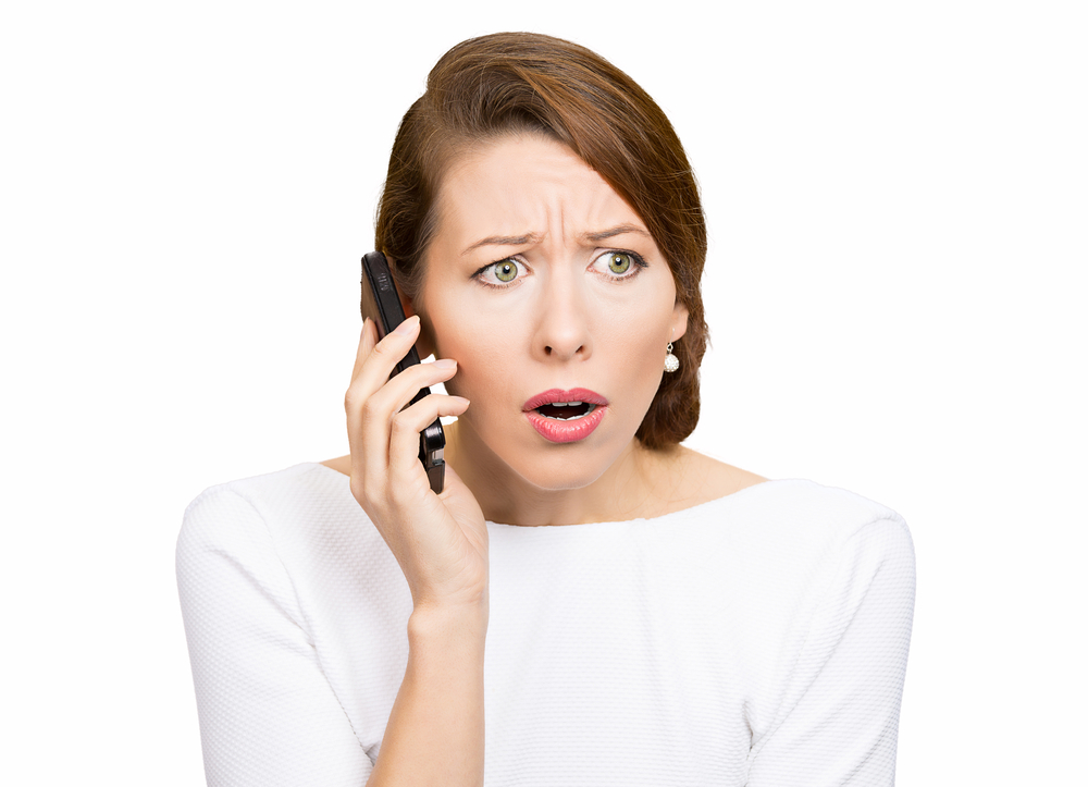 Closeup portrait, headshot, stressed shocked young business woman, talking on cellular, having unpleasant conversation receiving bad news isolated white background. Human emotions, facial expression