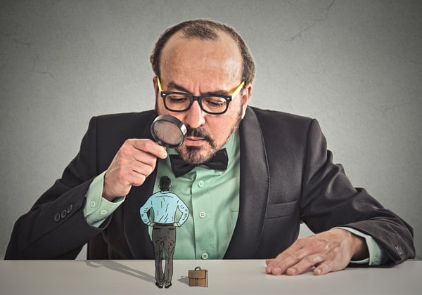 Curious corporate businessman skeptically meeting looking at small employee standing on table through magnifying glass isolated office grey wall background. Human face expression, attitude, perception-2