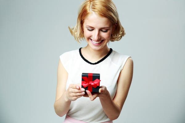 Smiling beautiful young woman holding an open jewelery gift box